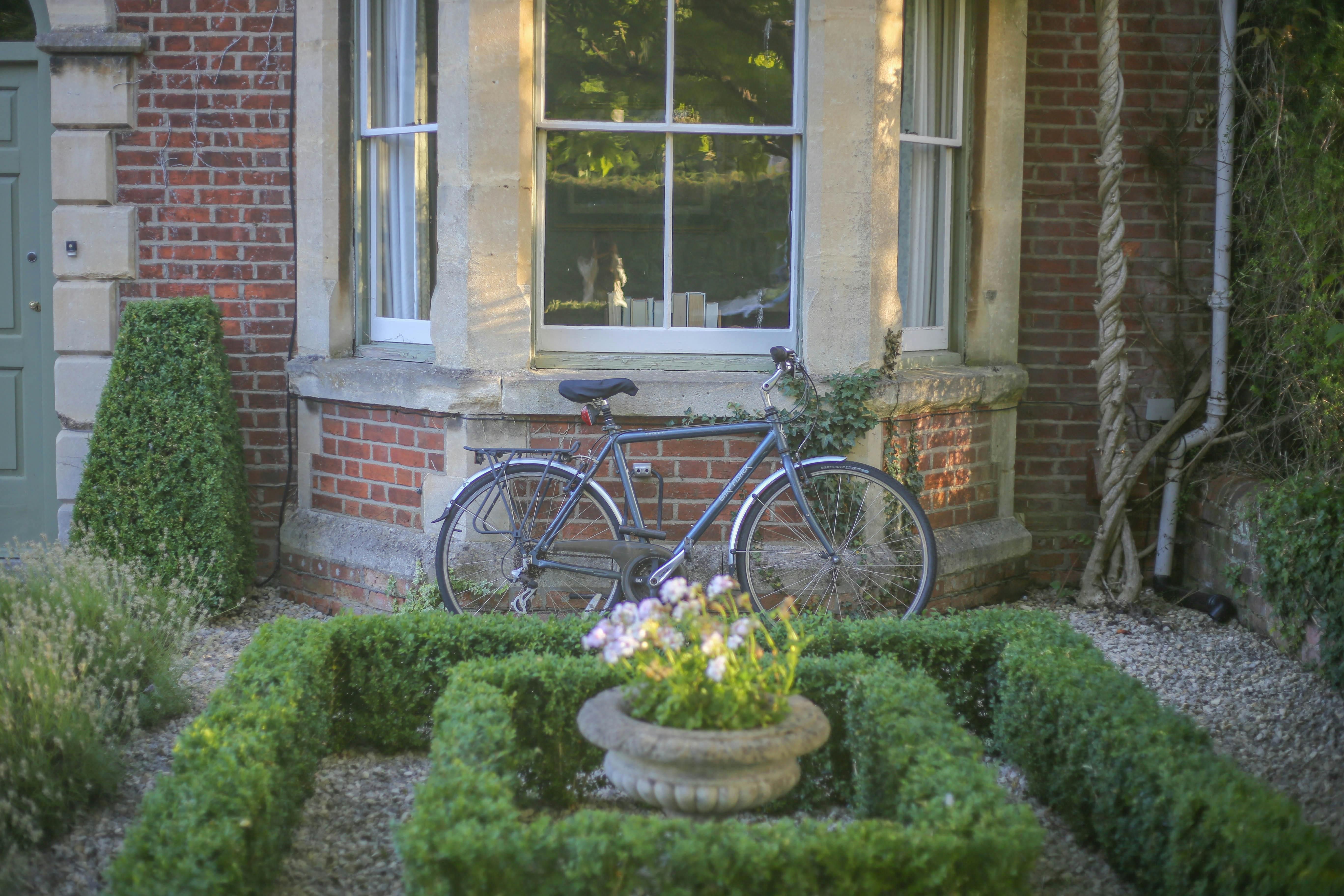 Bike leaning up against the front of a home under the window. 